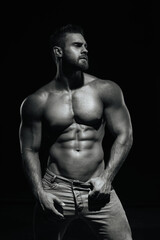 Fototapeta na wymiar Male fitness model Konstantin Kamynin posing shirtless on black background