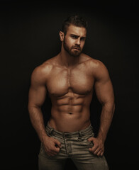 Fototapeta na wymiar Fitness male model standing on dark background