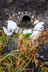 Stormwater management, outlet pipe for excess rainwater, sandbags, and garden plantings

