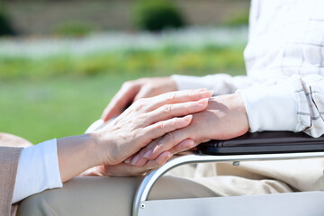 車椅子に乗る男性の手を握る女性