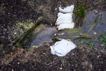 Stormwater management, inlet pipe for excess rainwater, sandbags, and garden plantings
