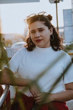 Mujer joven latina frente al sol en un evento social en la calle