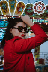 Mujer latina con gafas de sol en el atardecer de un parque de diversiones