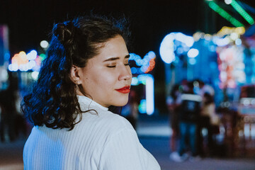 Mujer latina bonita sonríe en parque de diversiones de noche