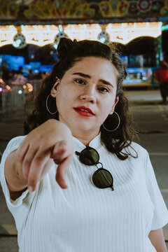 Mujer latina bonita apunta el dedo directamente a la cámara en el parque de diversiones
