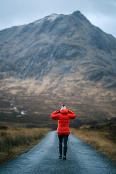Woman walking on a road in Glen Etive, Scotland