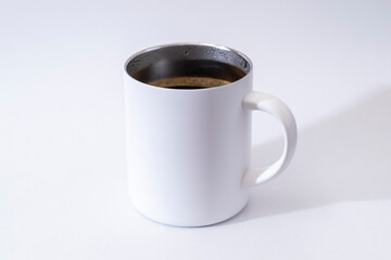 コーヒーの入った保温性のある白いマグカップ