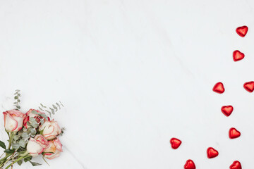 Valentine's rose bouquet with red chocolate hearts on a white marble background