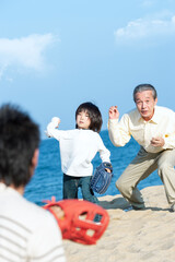 砂浜で野球をする三世代家族