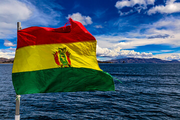 The national flag of Bolivia fluttering in the wind against Lake Titicaca background. Selective...