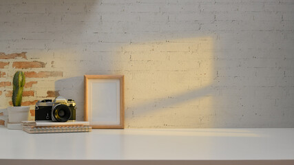 Workspace in home office room with camera, cactus pot, mock up frame and copy space