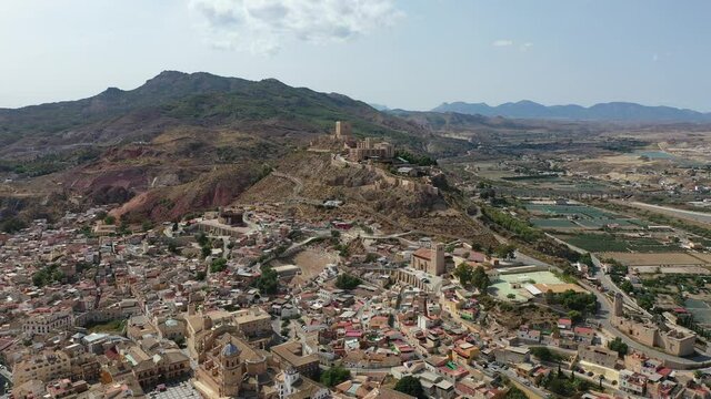 Aerial view of Spanish city of Lorca overlooking Collegiate church of St. Patrick and ancient castle on hilltop on sunny autumn day. High quality 4k footage