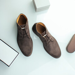 Men's suede shoes in cocoa color on a light background with objects.