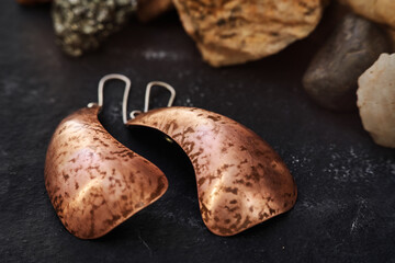 Handmade copper earrings on a black textured background. goldsmith's product. Special gifts