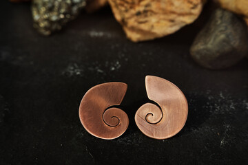 Handmade copper swirl earrings on a black textured background. Jewelry product. Special gifts    