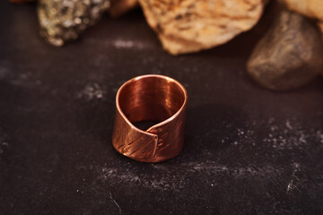 Obraz na płótnie Canvas Copper ring with tubular shape handmade on a black textured background. Jewelry product. Special gifts 