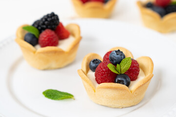 Delicious pastry mini fruit cream cheese pies or tart cakes with fresh raspberry, blueberry and blackberry