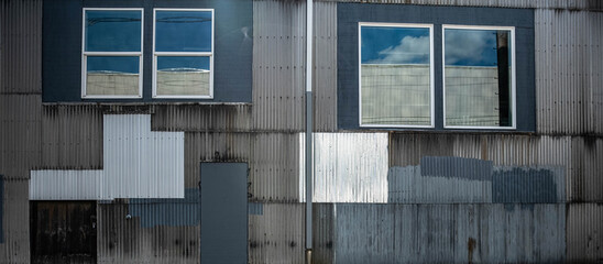 Facade of an industrial building with corrugated metal paneling and windows.