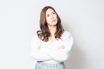 Fototapeta premium 白い壁の前に立って考え事をする若い女性