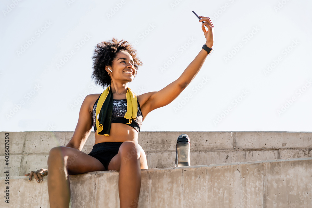 Wall mural Athlete woman taking a selfie with phone outdoors.