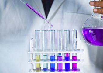 A scientist works in a chemistry lab, carefully mixing color solutions. Observing the reactions,...