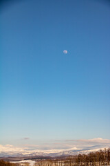 夕映えの雪山と空に昇る月
