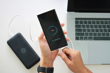 Close up Man holding smartphone charging battery from Power Bank type c port with using pd charging...