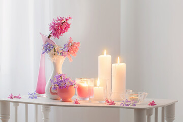 spring flowers and burning candles in white interior