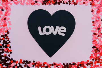 Black and red hearts with the words love on a pink background on Valentine's Day