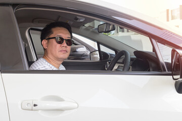 Asian man driving car and wearing dark glasses