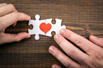 Puzzle pieces with heart joined togeather, hands of woman and man. Relationship concept