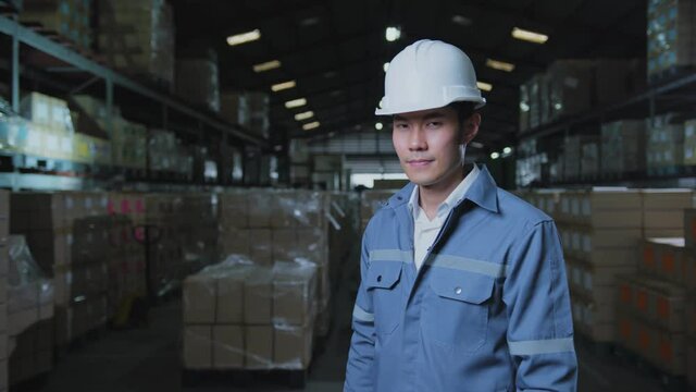 portrait of asian male professional enginner wearing uniform hardhat standing and smile with confident and cheerful in warehouse factory