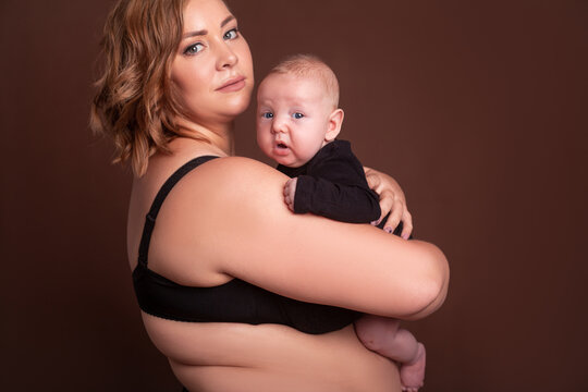 Overweight mother , with fat body after childbirth, holding newborn baby on the studio