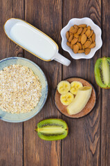 Ingredients for making milk porridge, oatmeal, milk, banana, kiwi top view, healthy food and hearty breakfast with fruits