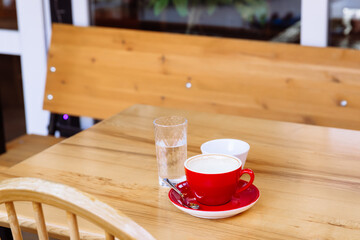 Dirty coffee cups, cappuccino and a glass of water stand on a wooden table.