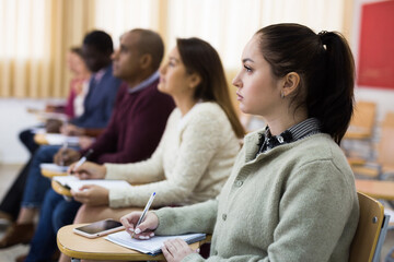 Side view of student group working on lecture in classroom, making notes