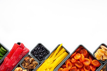 A set of dried fruits and candied fruit in rectangular and square boxes on a white background. A place for text. Winter healthy sweets. Winter vitamins. Vegan sweets.