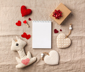 A blank notepad for your text surrounded by hearts, gift boxes on a linen tablecloth. Valentine's Day card. Copy space.