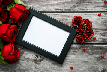 Top view of frame, red roses and heart on wooden with copyspace for Valentine, love and wedding concept.