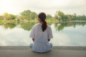 An Asian woman relaxing by the water in a park
