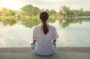 An Asian woman relaxing by the water in a park