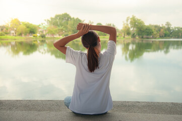 An Asian woman relaxing by the water in a park