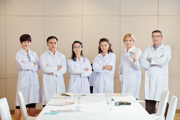 International group of scientists in labcoats standing in conference room after discussing advantages of new coronavirus vaccine