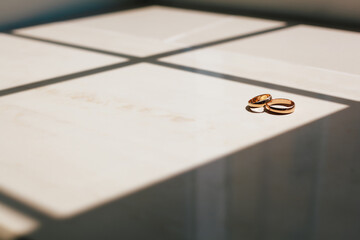 Beautiful wedding rings lie on wooden surface against background of bouquet of flowers. Declaration of love, spring. Wedding card, Valentine's Day greeting. Wedding rings. Wedding day details