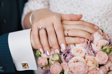 Hands newlyweds with donned rings on a bouquet of flowers