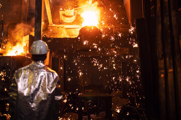 Melting iron in foundry and worker controlling the process iron casting and production. Metallurgy...