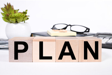 PLAN, text on wood cubes on a white background office desk. side view