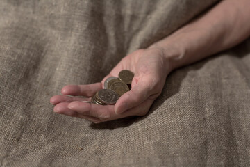 An old hand holds a handful of small coins.