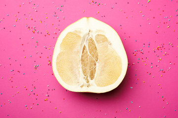 Half of ripe pomelo fruit and sprinkles on pink background