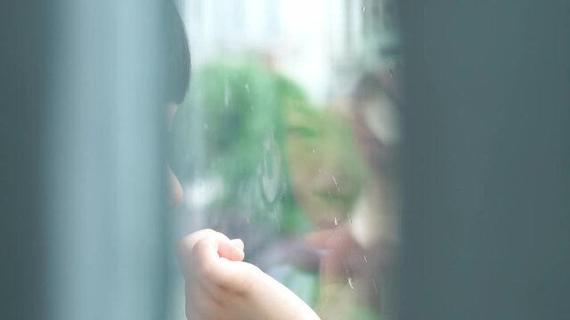 An Autistic child draw stick figure with finger on fogged glass window to develop social interaction. World autism awareness day, Mental health care, Child development, Autism Spectrum Disorder, ASD.